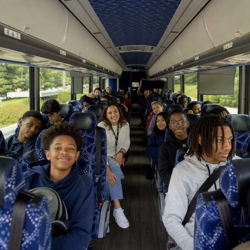 Group boarding a white charter bus for School Transportation transportation in San Jose